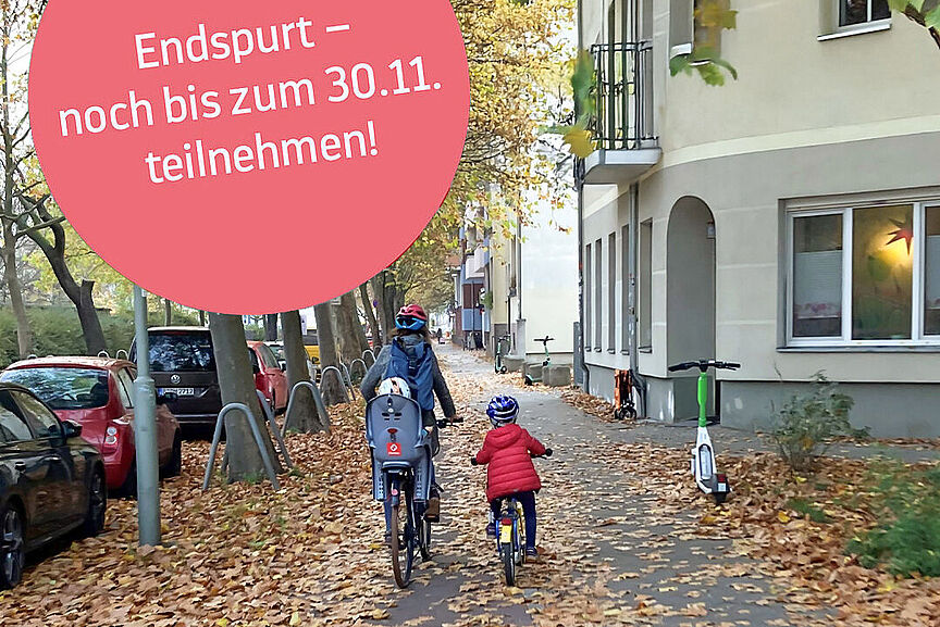 Radfahren im Herbst Eine Mutter und ihre Kinder fahren auf einem herbstlich mit Blättern gesäumten Gehweg.